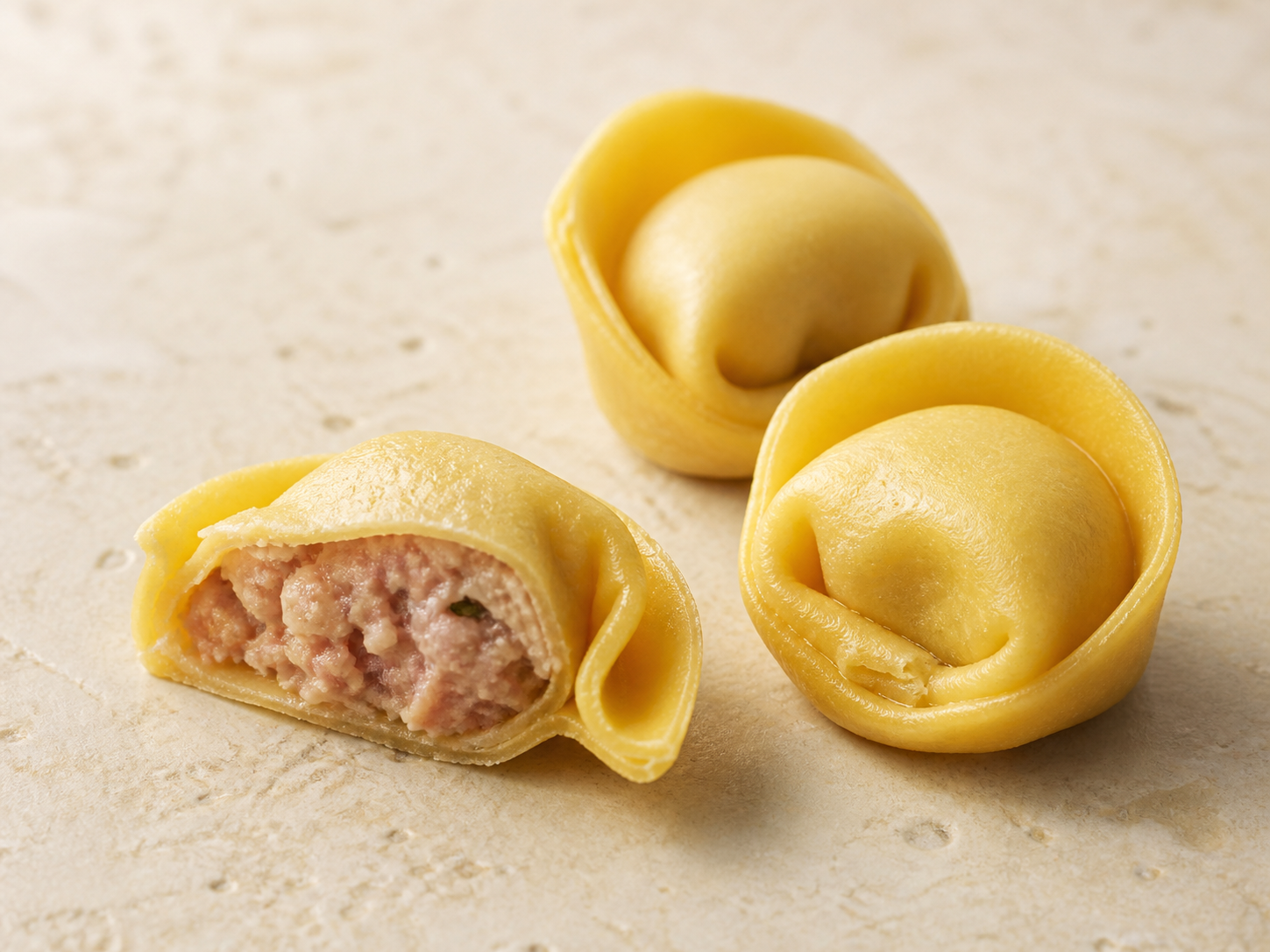 Tortellino Falconi aperto con ripieno visibile accanto a due tortellini interi